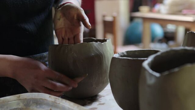 Mapuche Woman Potter's hands moistening raw clay vassal, craftswoman hands close up. Concept of creativity and art.