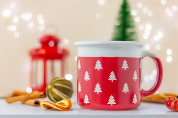 close up large red cup with white fir trees on table with dry lemon and cinnamon. celebration, winter holiday