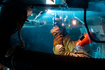 man working under a train using a welder 