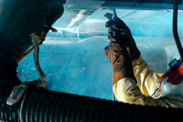 man working under a train using a welder 