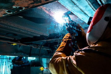 man working under a train using a welder 