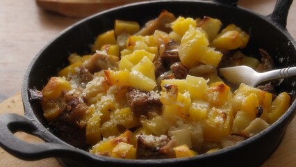 Pull back shot of Hot Baked Potato and Meat Skillet with Grated Cheese.