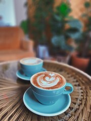 two cups of coffee on a table with a plant behind them