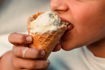 Close-up view of a boy eating ice cream in a waffle cup. Macro. Detailed view of a tongue in ice...