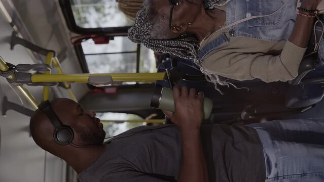 Man with headphones using smart phone standing in bus. Cinematic 4k. Vertical video.