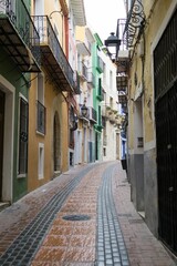 Vertical shot of a narrow street with colorful buildings in Alicante, Spain