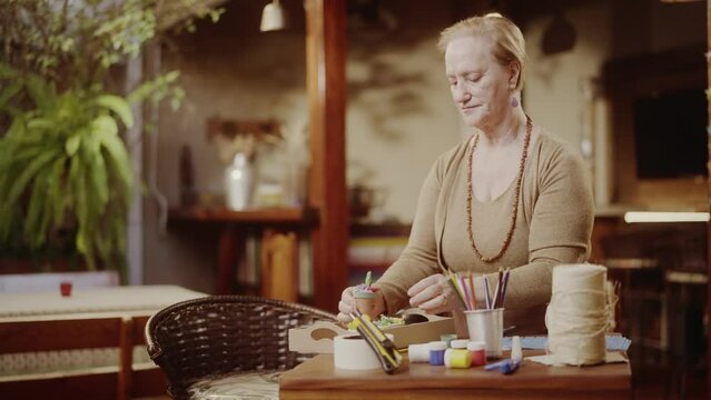 Mulher idosa sorridente apreciando o trabalho de ceramica em casa. Cinematico 4k.