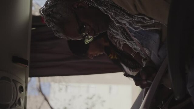 Mulher negra senior com estiloso cabelo afro, fazendo anotacoes em um caderno durante trajeto de onibus. Cinematico 4k. Video vertical.