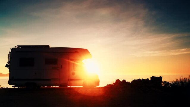 Camper vehicle camping on coast sea shore at sunrise. Adventure, travel with motor home.