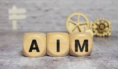 Ambition, mission and objective concept. Wooden cubes with text AIM and archery target with arrows icon.