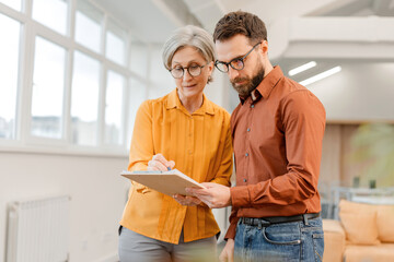 Business people, successful colleagues communication, brainstorming, sharing ideas, planning startup. Senior woman and  man working together in modern office. Meeting, teamwork, successful business © Maria Vitkovska