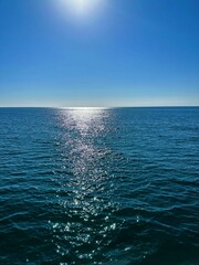 Vertical shot of a sea with sunlight under blue sky