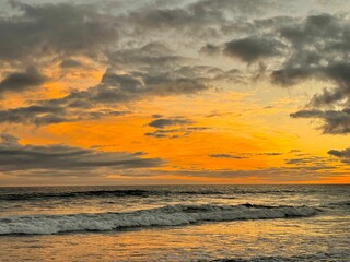 Naklejka na ściany i meble Scenic shot of a wavy sea under the fiery sky at sunset, cool for background