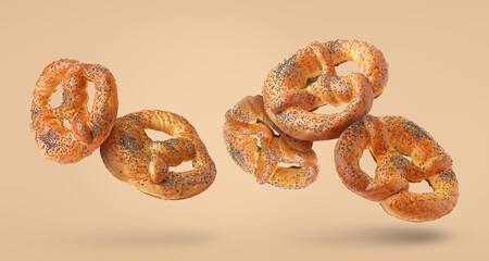 Tasty flying pretzels on beige background
