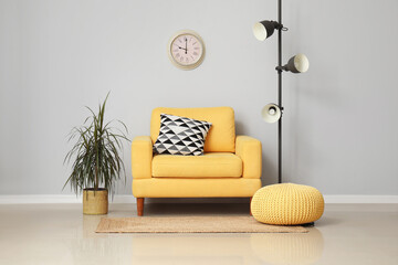 Yellow armchair with cushion and standard lamp near white wall