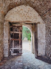 Vertical closeup shot of an old stone medieval house with arched entrance and wooden door
