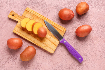 Wooden board with slices of fresh raw potato on pink background