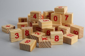 Wooden cubes with numbers and mathematical symbols on light background
