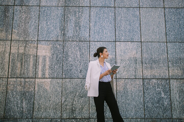 Beautiful business woman looking away while standing infront of the wall