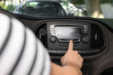 Obraz premium Choosing favorite radio. Man pressing button on vehicle audio in car, closeup