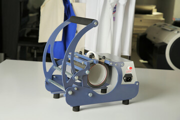 Printing logo. Heat press with cup on white table