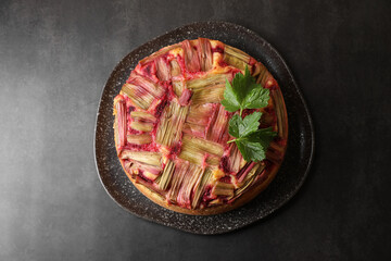 Freshly baked rhubarb pie on black table, top view