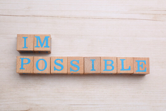 Motivation concept. Changing word from Impossible into Possible by removing cubes on light wooden table, flat lay
