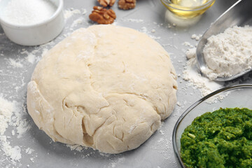 Making delicious pesto bread. Raw dough and ingredients on grey table, closeup