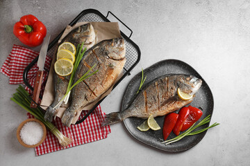 Seafood. Delicious baked fish served with green onion, bell pepper and lemon on light textured table, flat lay