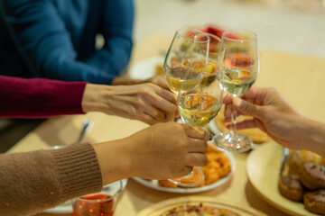 close up glasses of clinking glasses of champagne with lighting. Dinner party with drinking of champagne. hands holding clear glass with alcohol in yellow shine reflect.