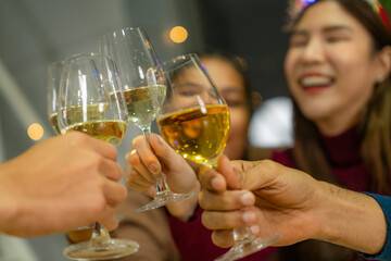 close up glasses of clinking glasses of champagne with lighting. Dinner party with drinking of champagne. hands holding clear glass with alcohol in yellow shine reflect.