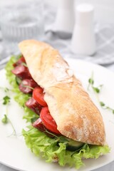 Delicious sandwich with sausages and vegetables on white table, closeup