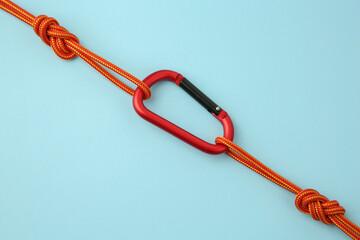 One metal carabiner with ropes on light blue background, top view
