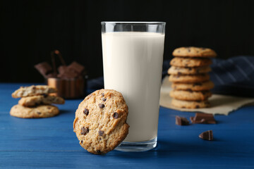Tasty chocolate chip cookies and glass of milk on blue wooden table