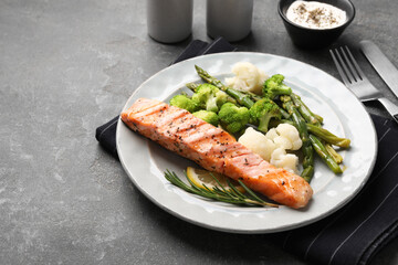 Healthy meal. Piece of grilled salmon, vegetables, asparagus and rosemary served on grey textured table, closeup. Space for text