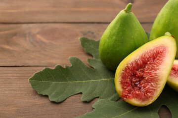 Cut and whole green figs on wooden table, closeup. Space for text