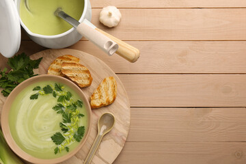 Delicious leek soup served on beige wooden table, flat lay. Space for text