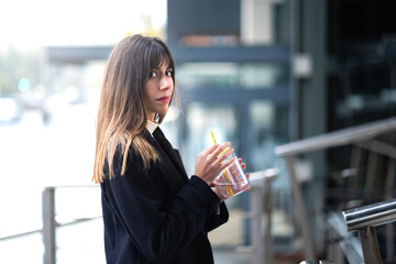 Woman sips water, glassy backdrop.