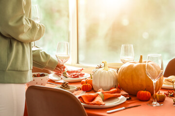Woman decorating table for Thanksgiving dinner in modern dining room, closeup