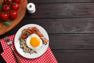 Tasty boiled oatmeal with fried egg, bacon and tomato served on wooden table, flat lay. Space for text