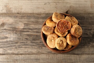 Bowl with tasty dried figs on wooden table, top view. Space for text