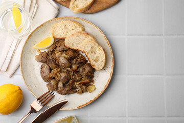 Tasty fried chicken liver with onion served on white tiled table, flat lay. Space for text