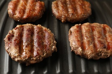 Delicious hamburger patties cooking on electric grill, closeup