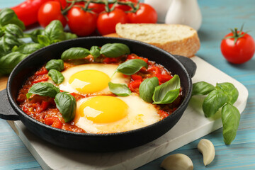 Delicious Shakshuka served on light blue wooden table, closeup