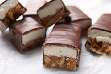 Tasty chocolate bars with nougat and nuts on white table, closeup