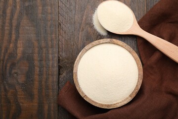 Uncooked organic semolina in bowl and spoon on wooden table, top view. Space for text