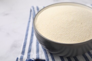 Bowl of uncooked organic semolina on white marble table, closeup. Space for text