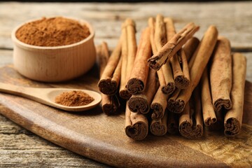 Cinnamon powder and sticks on wooden table, closeup