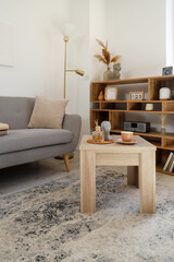 Wooden coffee table with cup of hot tea, reed diffuser and decor in modern living room
