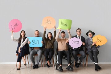 Business people holding speech bubbles with words near light wall